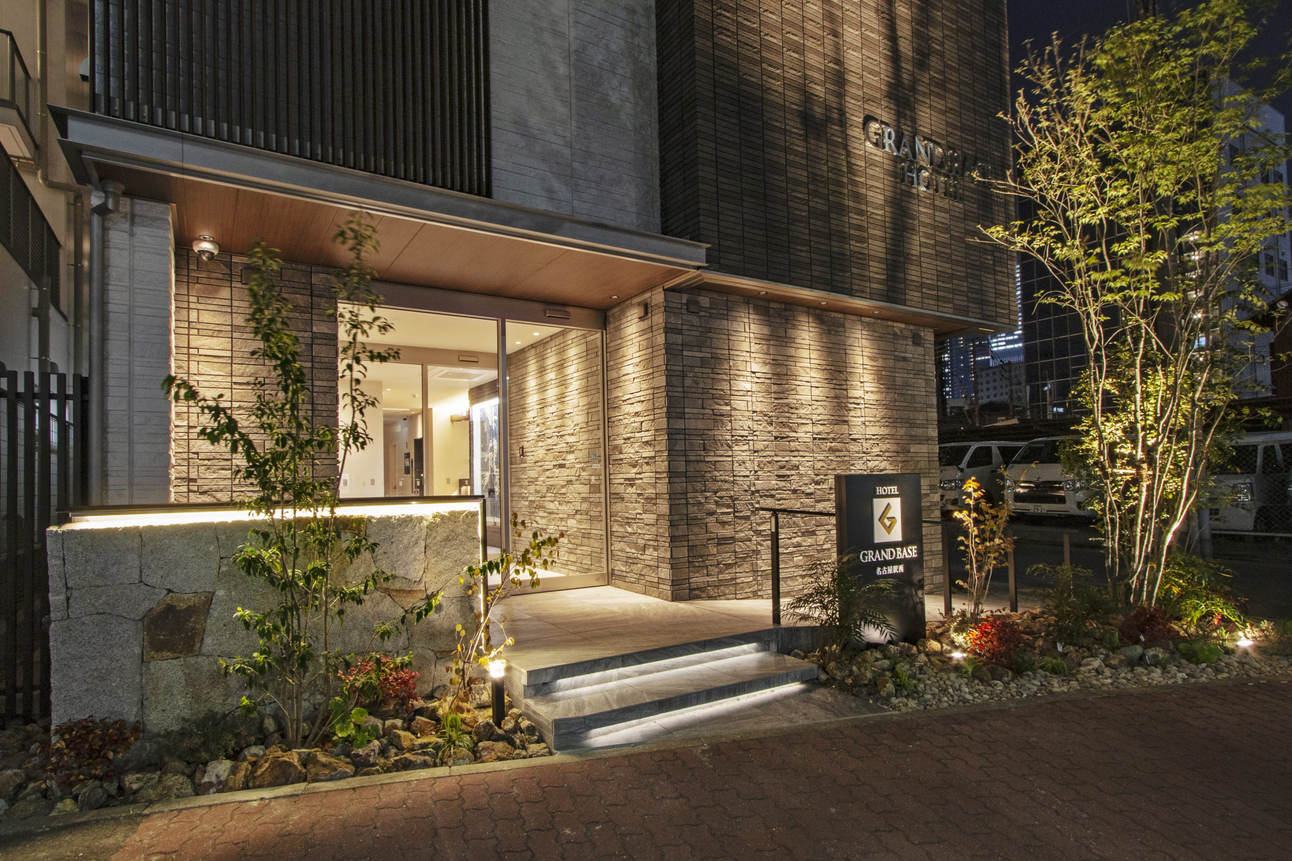 グランドベース名古屋駅西 — 名古屋市中村区竹橋町 · 全7室に洗濯機とキッチンを備えるアパートメントホテルの夜景エントランス