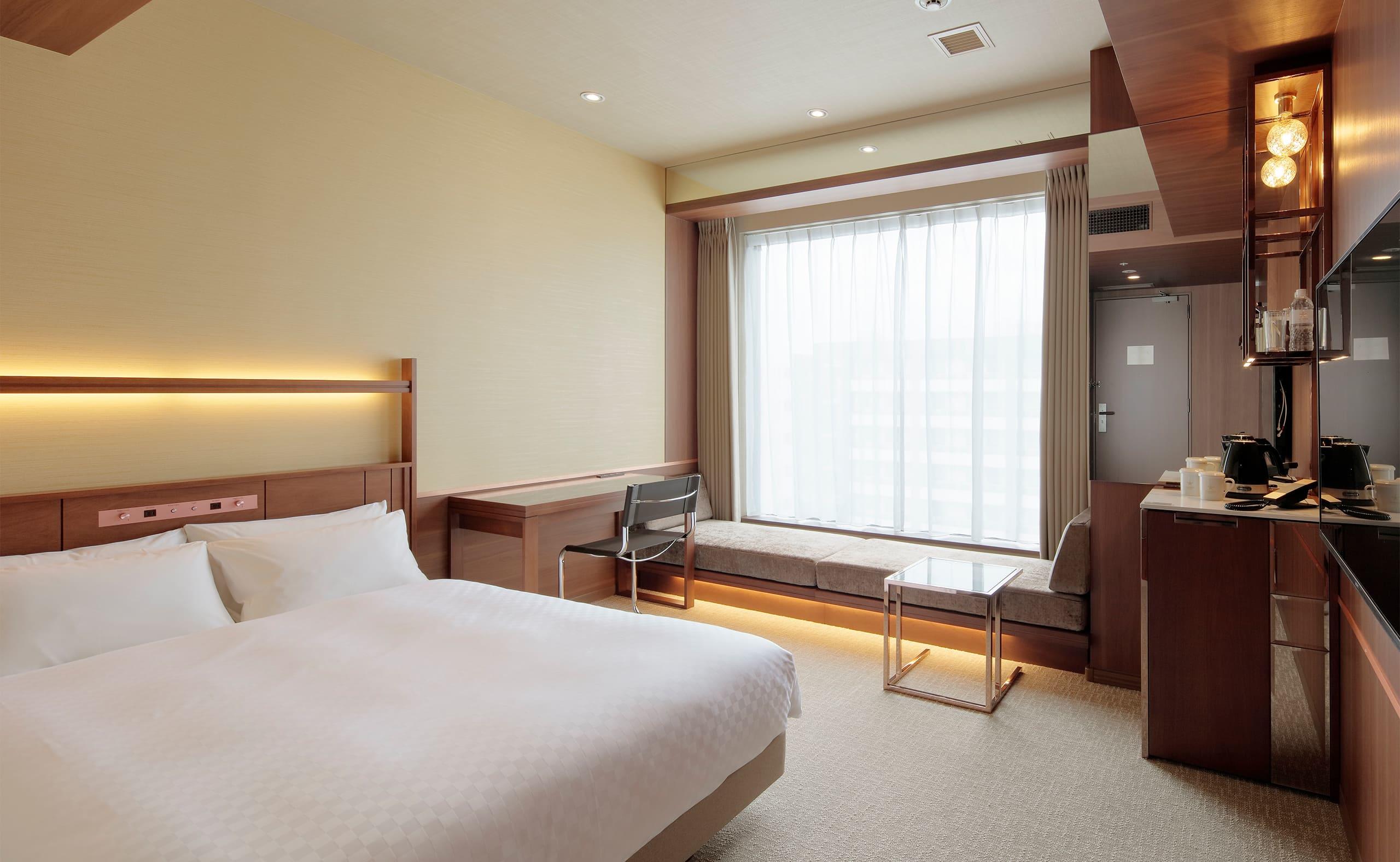 カンデオホテルズ熊本新市街 — 熊本市中央区新市街 · 広さ18㎡のダブルルーム、窓際にベンチソファを置いた客室