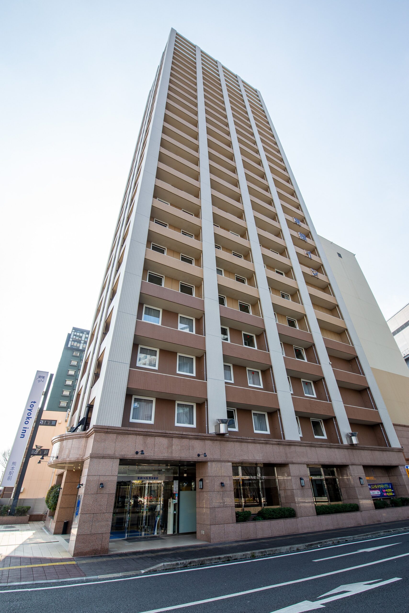 東横INN熊本駅前 — 熊本市西区春日 · JR熊本駅白川口（東口）から徒歩2分、青空の下の建物外観