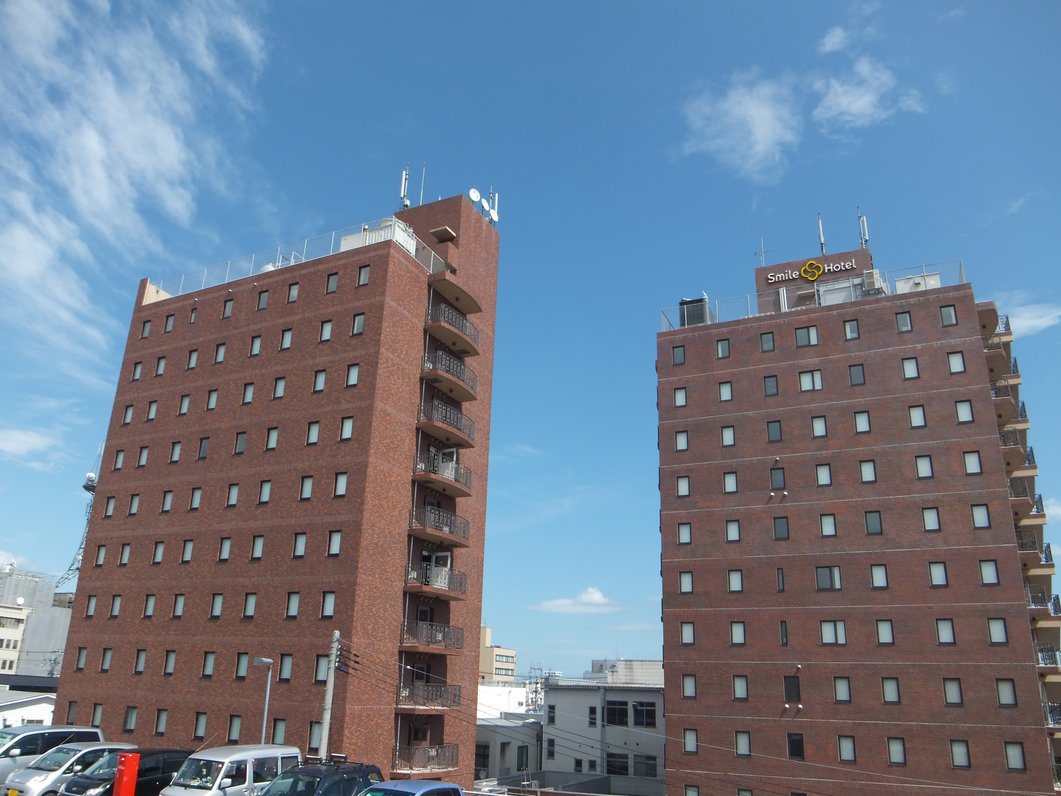 スマイルホテル古川 — 大崎市古川駅前大通 · レンガ色の高層棟が2棟並ぶ外観。右棟の屋上にスマイルホテルの看板
